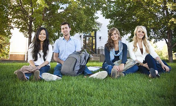 smiling students sitting on grass at university