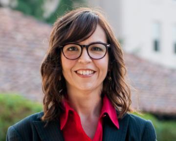 A person wearing glasses and smiling in an outdoor setting. image link to story
