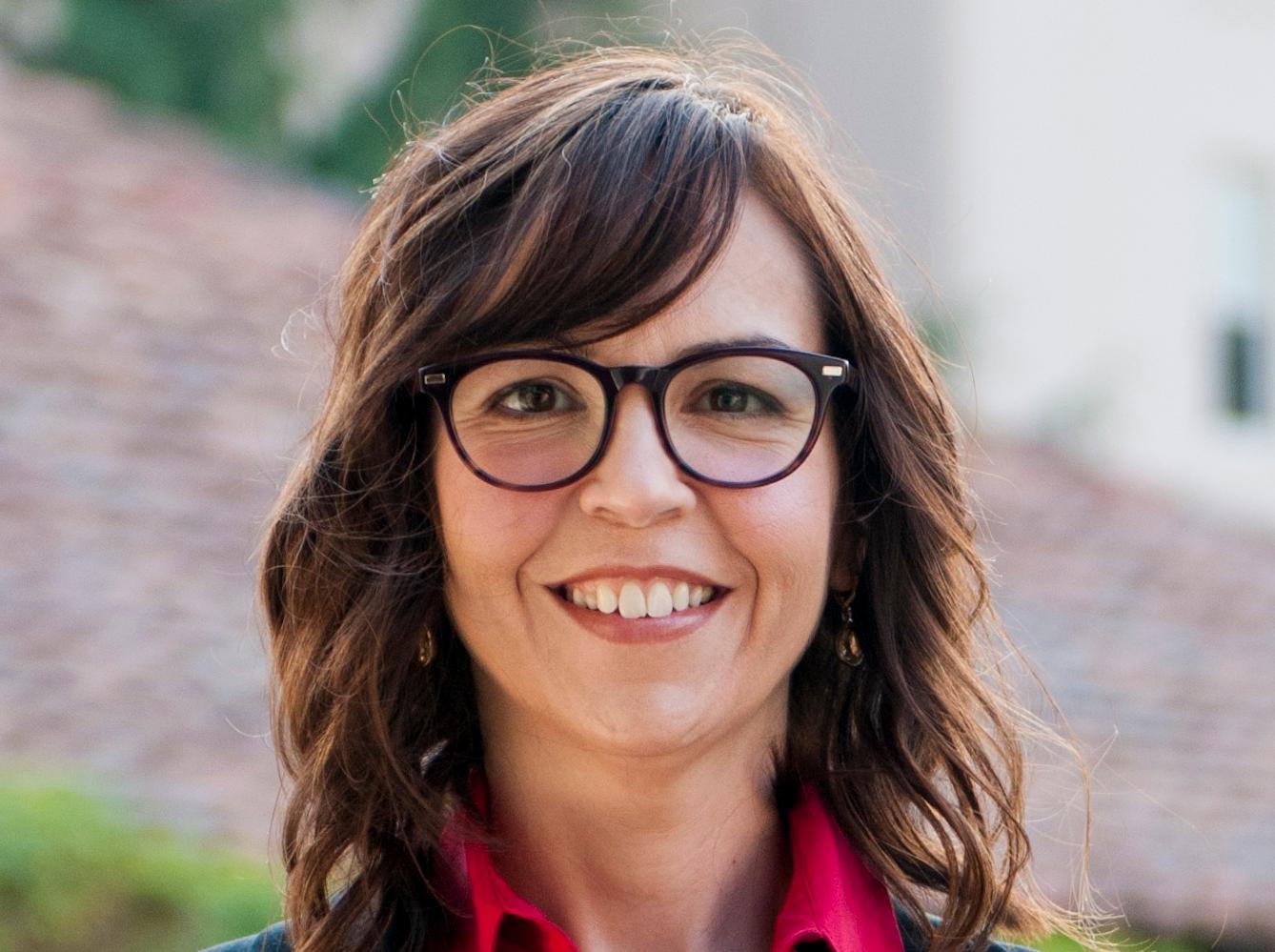 A person wearing glasses, a red shirt, and a black blazer. image link to story