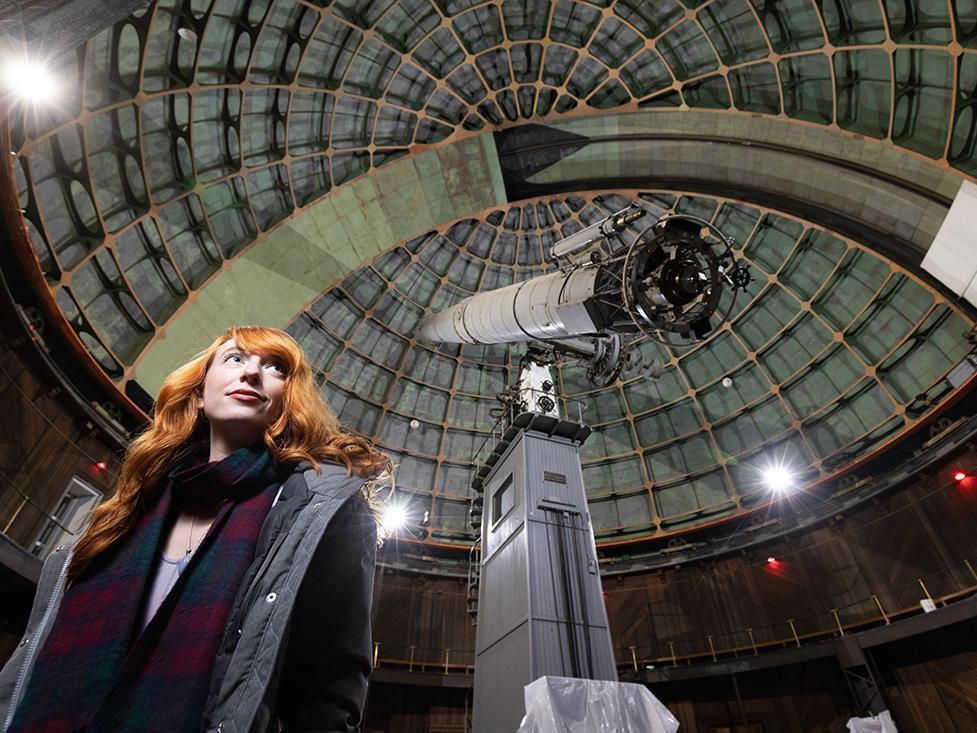 Kimberly Dill standing below a large astronomical telescope.