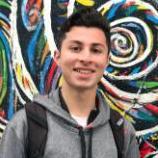 A person smiling in front of a colorful, swirly mural. image link to story