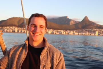 A person smiling in front of a scenic waterfront view. image link to story