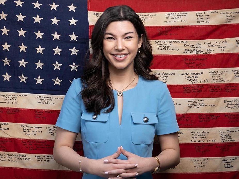 Jordan Tachibana in front of American flag signed by Japanese internment survivors.