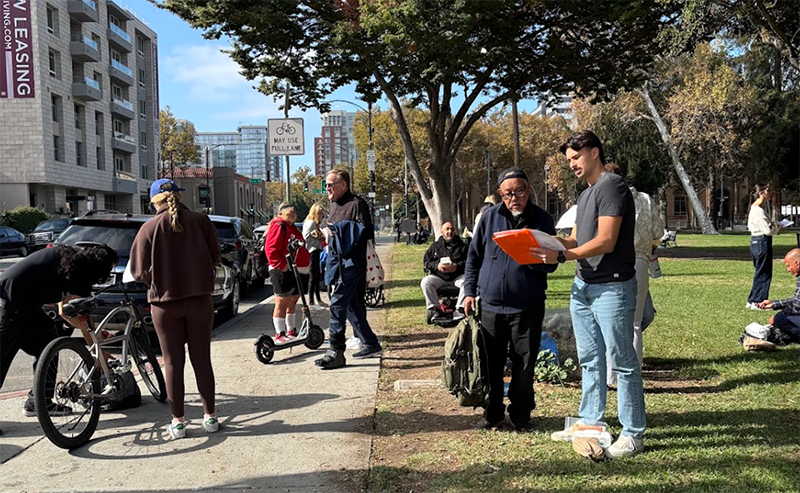 Volunteers interviewing unhoused men and women in an urban park.