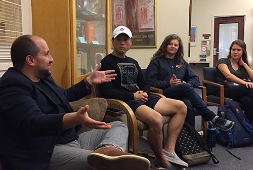 A man and four students having a discussion indoors.