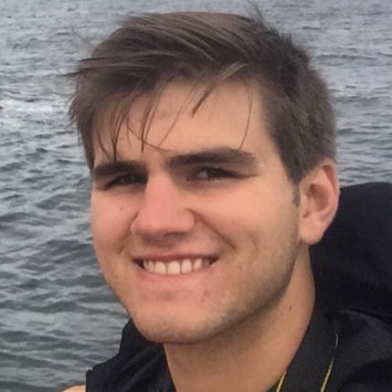 A person smiling with water in the background.