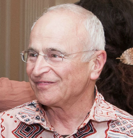 Smiling person wearing a patterned shirt with a blurred background. image link to story