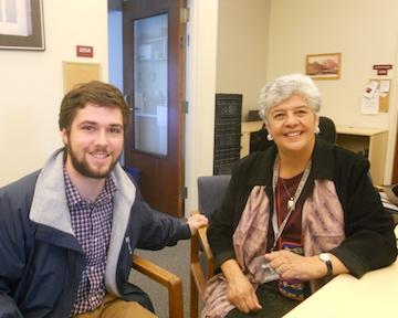 Two people seated indoors, smiling at the camera. image link to story