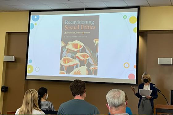 People at a book launch event with a speaker at the front.