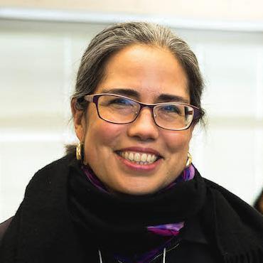 Dr. Tamayo-Moraga smiling with students in a classroom setting. image link to story