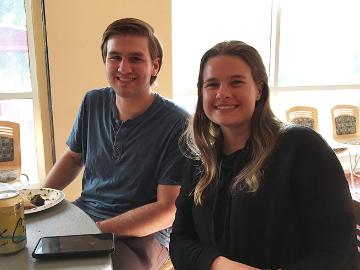Two people smiling while seated indoors with a laptop.