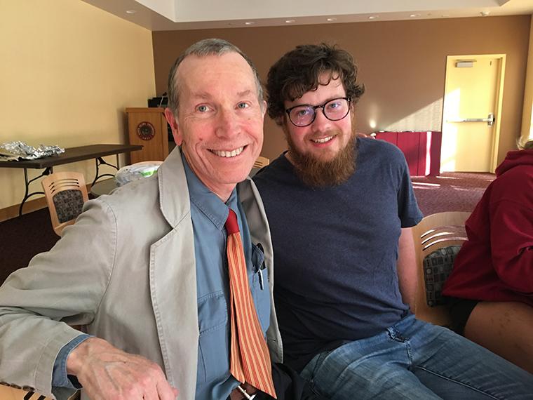 Two people sitting and smiling in a cozy room.