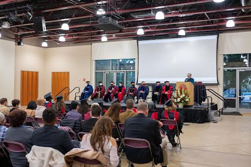 speaker at podium in front of small graduation ceremony