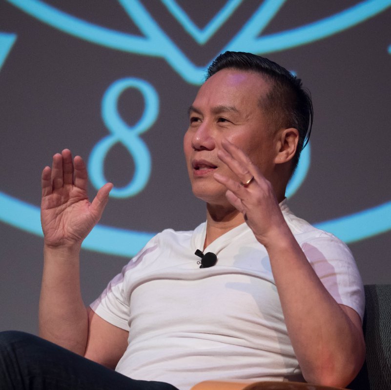BD Wong speaking on stage with a SCU seal backdrop 