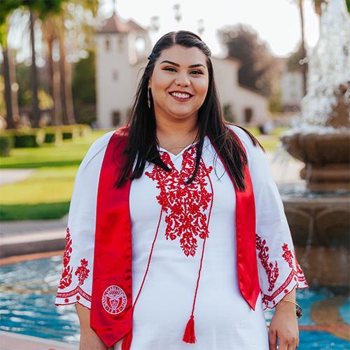 A person wearing a red and white outfit stands in front of a fountain. image link to story