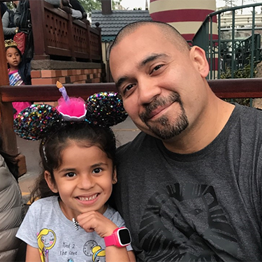 A man smiling with a young girl at an amusement park image link to story