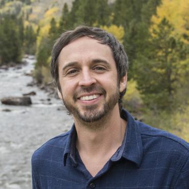 A person standing by a river with trees in the background. image link to story