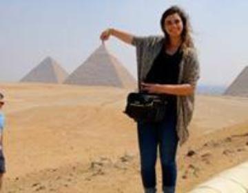 A person posing in front of pyramids, playfully holding one in perspective. image link to story