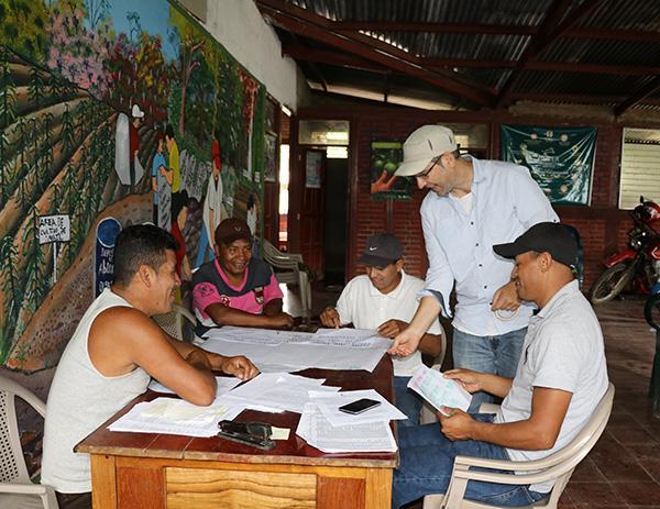 Several people gather around a table, one standing and others sitting.