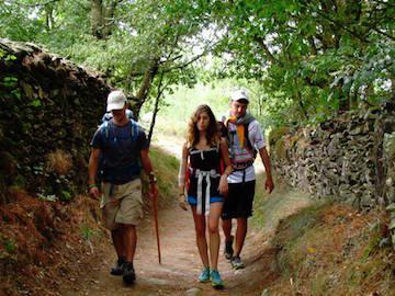 Three people walking down a shaded trail on the Camino de Santiago.