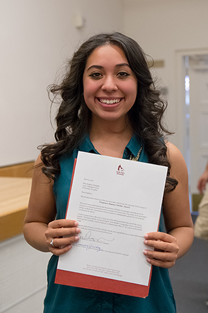Person holding up a paper with text and smiling.