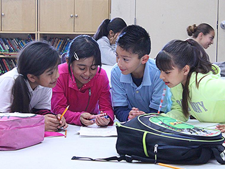 Four children sitting at a table, engaged in arts and crafts activities. image link to story