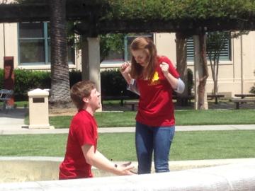 Two people in red shirts talking outdoors. image link to story
