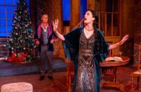 A woman in a 1920s dress and a man in a velvet smoking jacket in a scene from from The Games Afoot