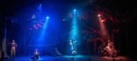 3 spotlights on stage highlighting 3 couples in a glen in a scene from Into the Woods