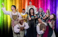 Joseph and the Amazing Technicolor Dreamcoat cast photo in front of a rainbow shimmer backdrop