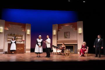 Inside of a 1930s mansion with 2 maids, 2 men in tuxedos and 2 women in evening dress