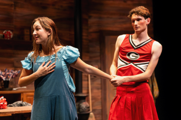 A guy in a red cheerleading outfit pulling the arm of a woman in blue