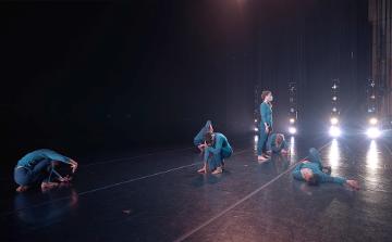 Onstage shot of 4 modern dancers on the ground and one standing
