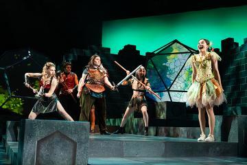A fairy on a fantastical stage with 3 female D&D questers and a man dressed as the devil