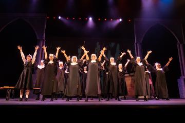 Sister Act nun's chorus group singing with arms raised to Heaven