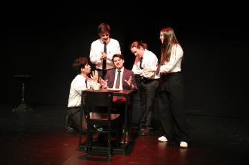 4 waiters crowded round a man seated at a table
