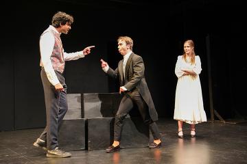 2 men in an argument with a woman in white looking on