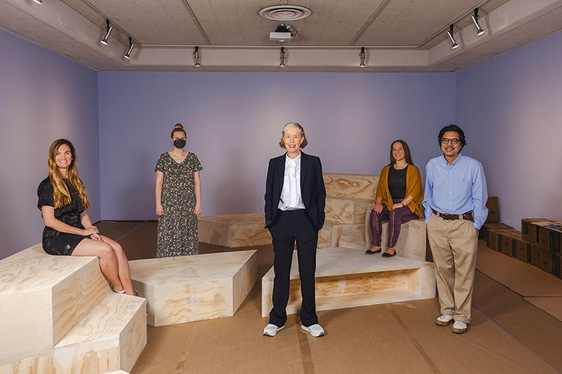 Five people in gallery space smiling at camera