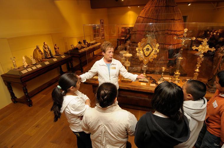 California History docent giving a tour of the museum's mission exhibit to school children.