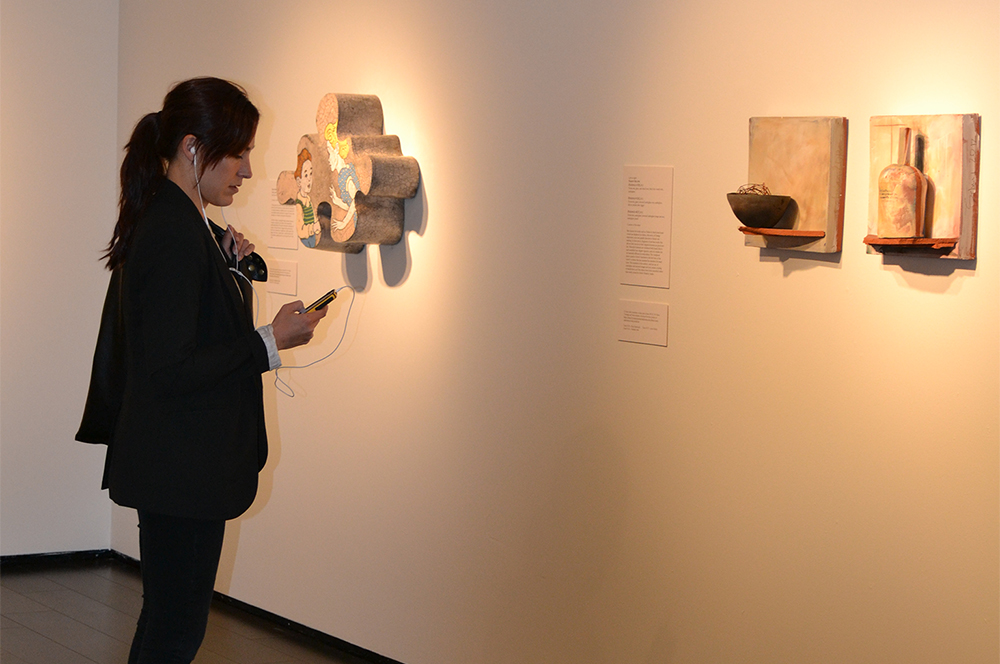 Woman listening to music and looking at ceramic artworks on display.
