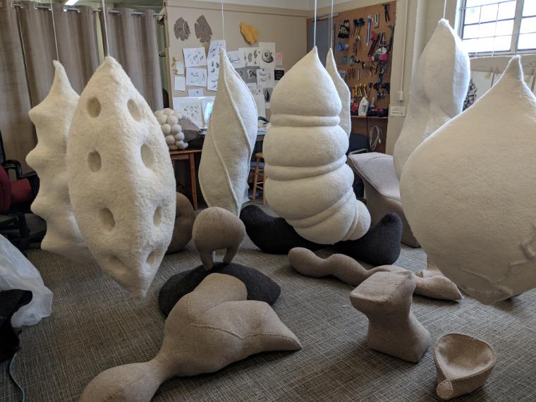 felt forms hanging from ceiling and others laying on the ground