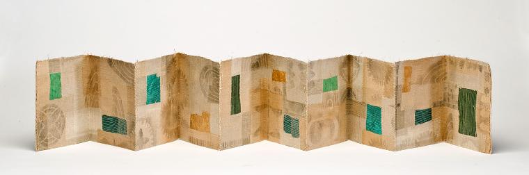 Photograph of accordion-style book art piece predominantly yellow and tan in color with blue and green rectangles.