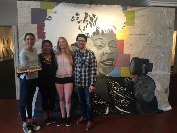 Students and staff stand with sheet cake in front of Ella Fitzgerald mural