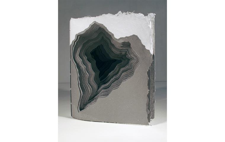 Artwork created from a book with subsequent layers cut narrower creating a recession into the book