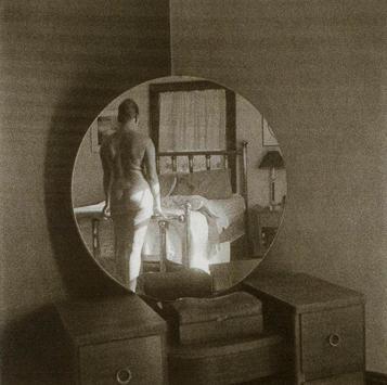black and white square photograph of figure reflected in circular mirror on a vanity 