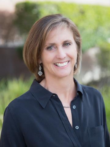 A woman wearing a black shirt, smiling outdoors. image link to story