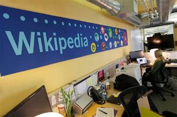 Office with a large blue Wikipedia banner on the wall and people working at desks. image link to story