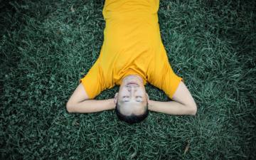 man resting happily on grassy lawn