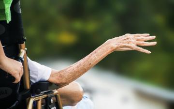 an elderly person in wheelchair with outstretched arm