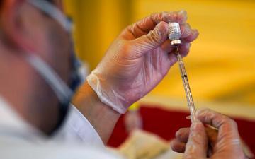 Medical professional holding a syringe and a vile of covid-19 vaccine